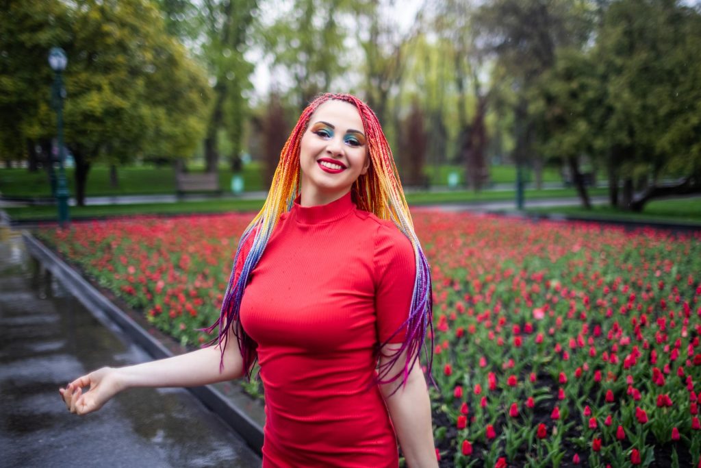 Femme rousse souriante propose téléphone rose dans un jardin fleuri