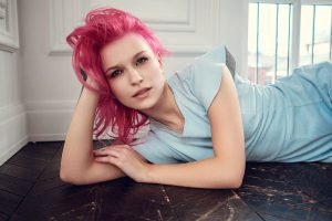 Louanne allongée au sol en tenue bleue, cheveux roses sensuels