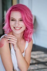 Louanne souriante aux cheveux rose vif pour Téléfonsex sensuel