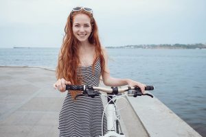 Sarah souriante en robe près du lac avec vélo, conversations sensuelles