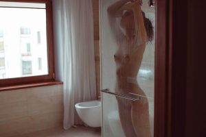 Kim nue sous la douche derrière une paroi embuée